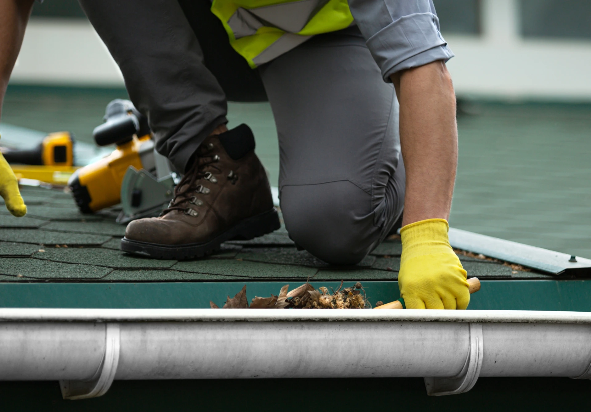 A Man Worker Is Cleaning a Clogged Roof Gutter from Dirt,