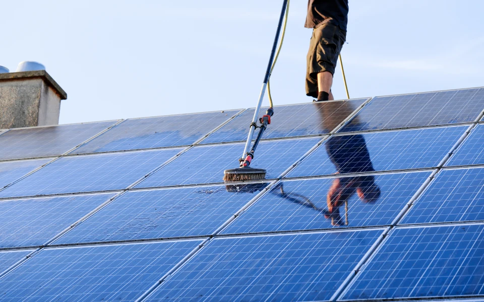 Cleaning solar panels with brush and water