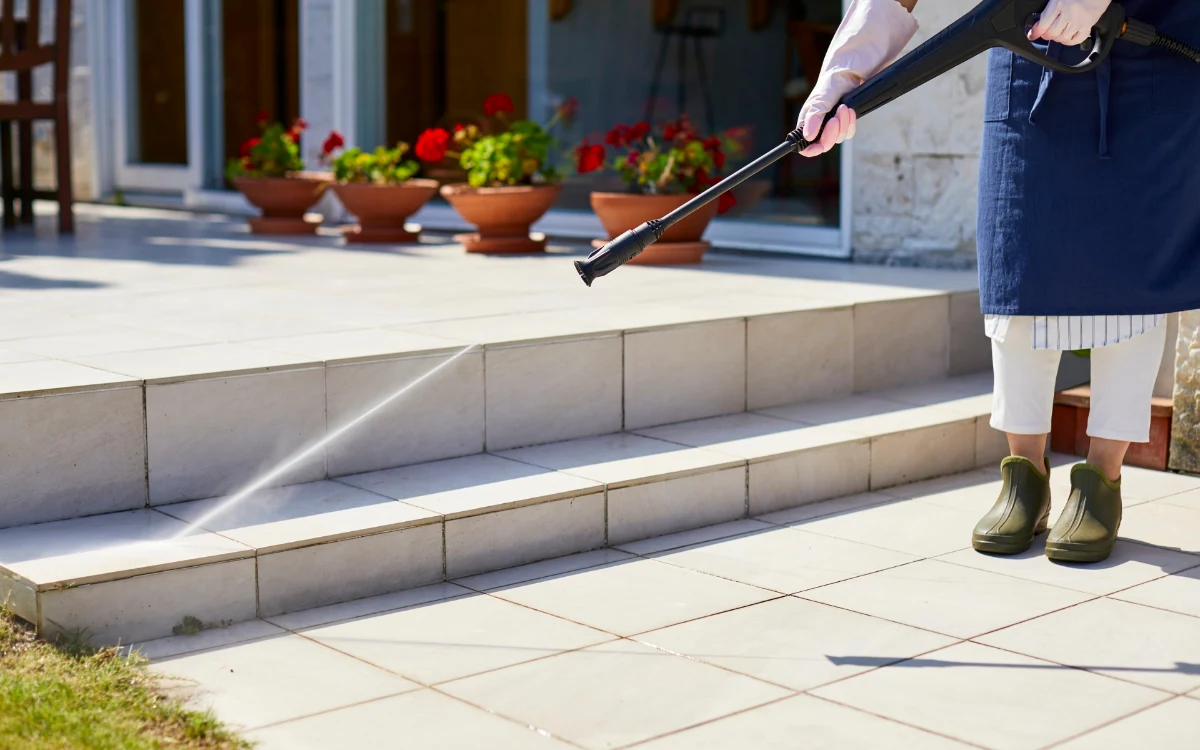 Person Cleaning Outdoor Tiles with a Pressure Washer