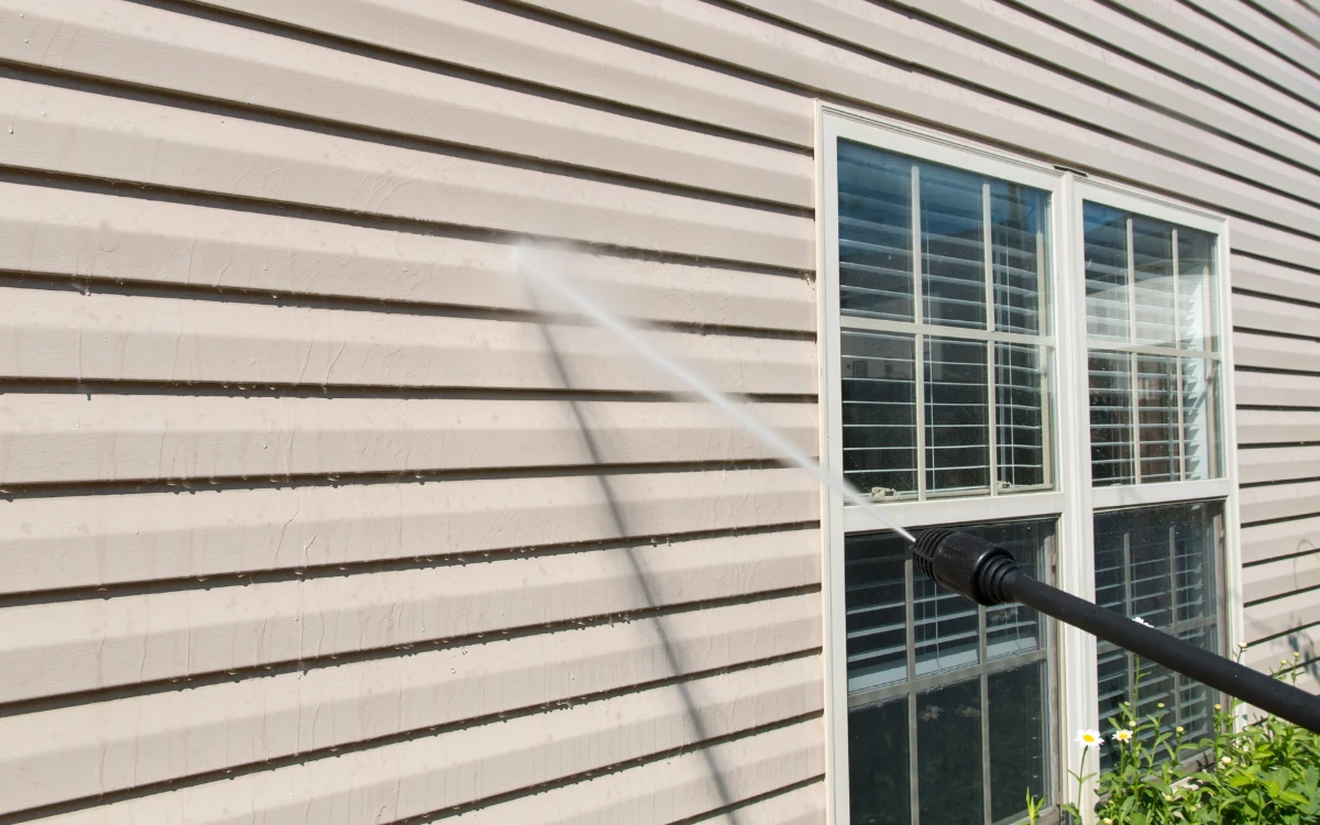 Power washing the side of a building to remove dirt and grime